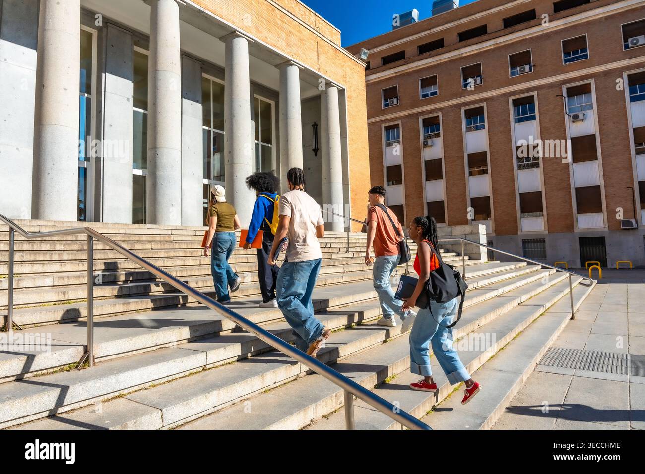 Diverse students walking up stairs on university campus Stock Photo