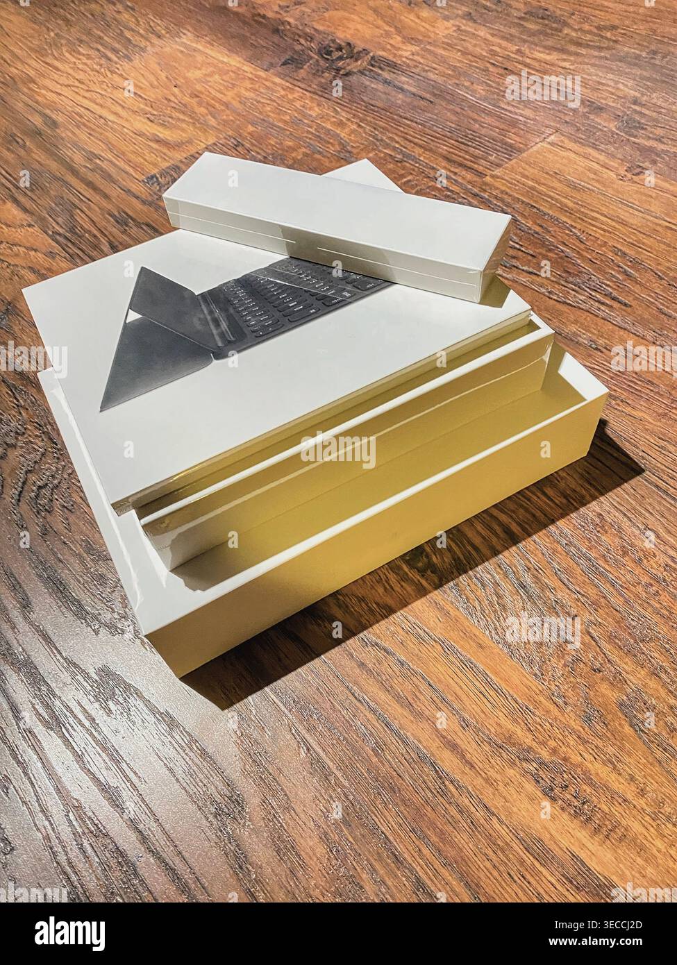 Minimalist composition of stacked technology packaging boxes on a wooden surface. Clean design, warm lighting and modern aesthetic create a concept - Smartphone Captured Stock Image