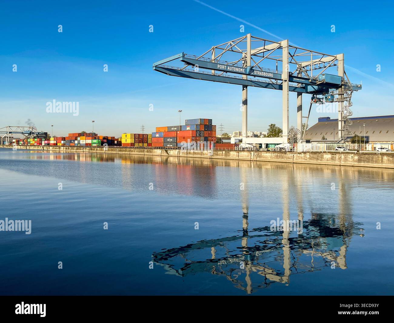 Strasbourg, France - 11 April 2022: Heavy crane on the quayside of the city's container terminal on the Rhine River, with reflection in still water. - Smartphone Captured Stock Image