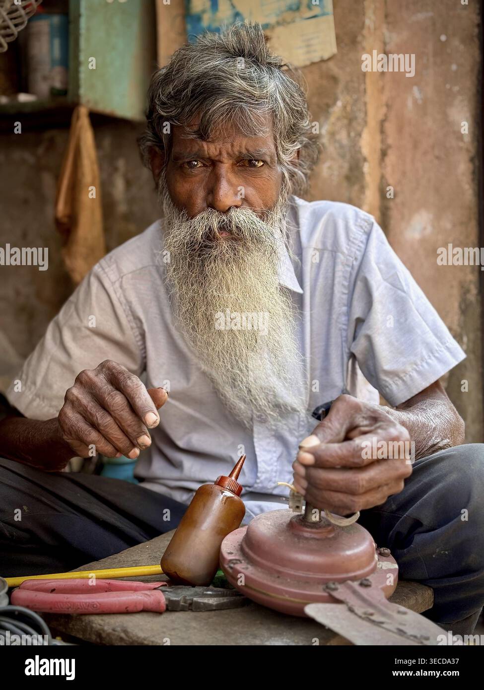 Elderly man with big beard working with tools in a craft environment, India Stock Photo