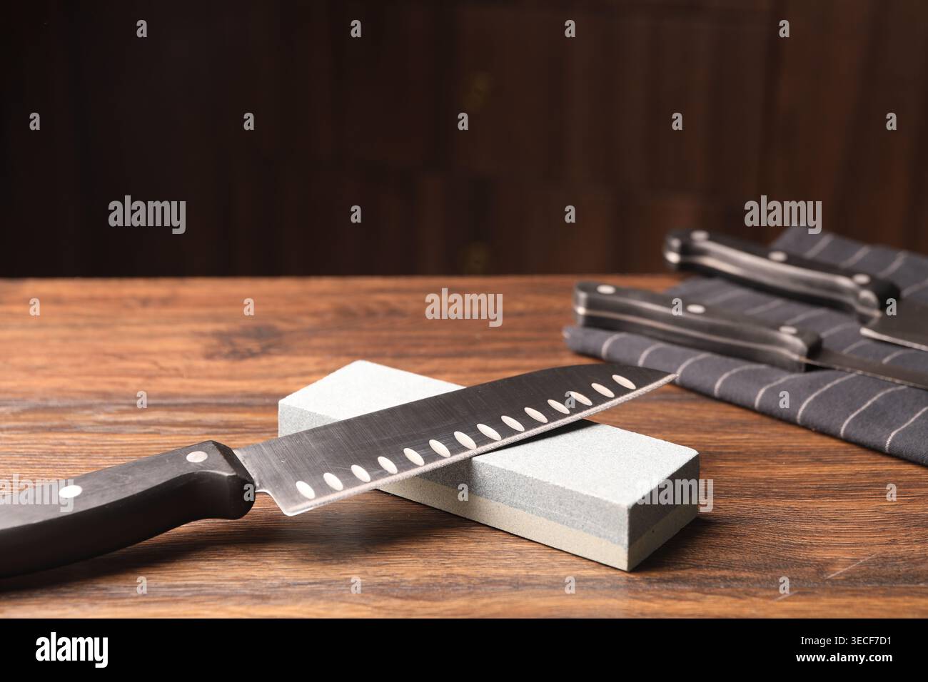 Sharpened knife and whetstone on wooden table. Space for text Stock Photo