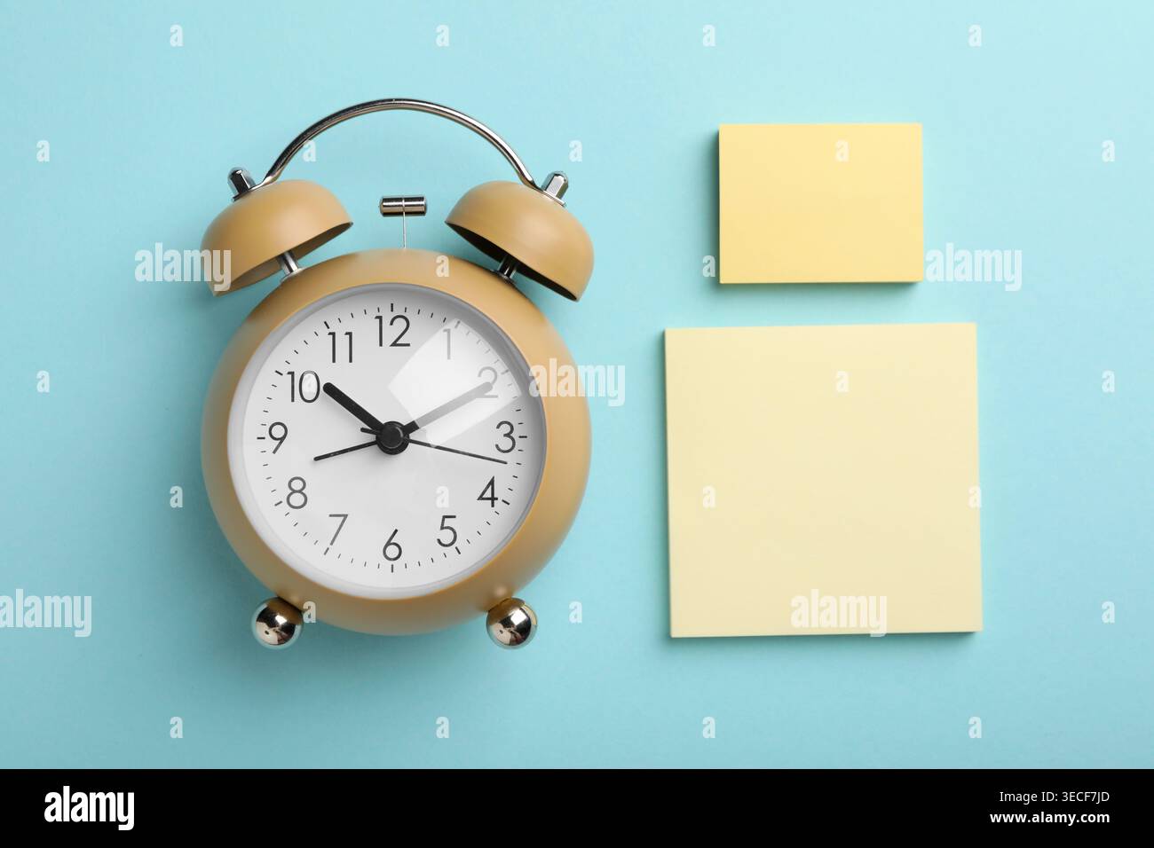 Reminder. Alarm clock and sticky notes on light blue background, flat lay Stock Photo