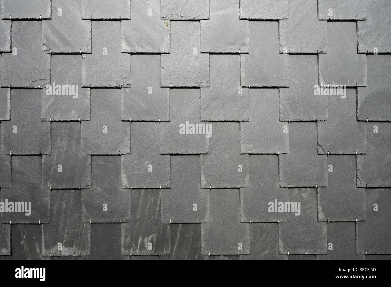 Overlapping dark slate tiles forming textured geometric roofing surface Stock Photo