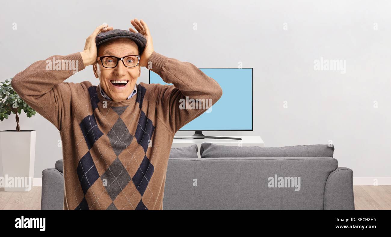 Surprised elderly man holding his head in front of a tv screen Stock Photo