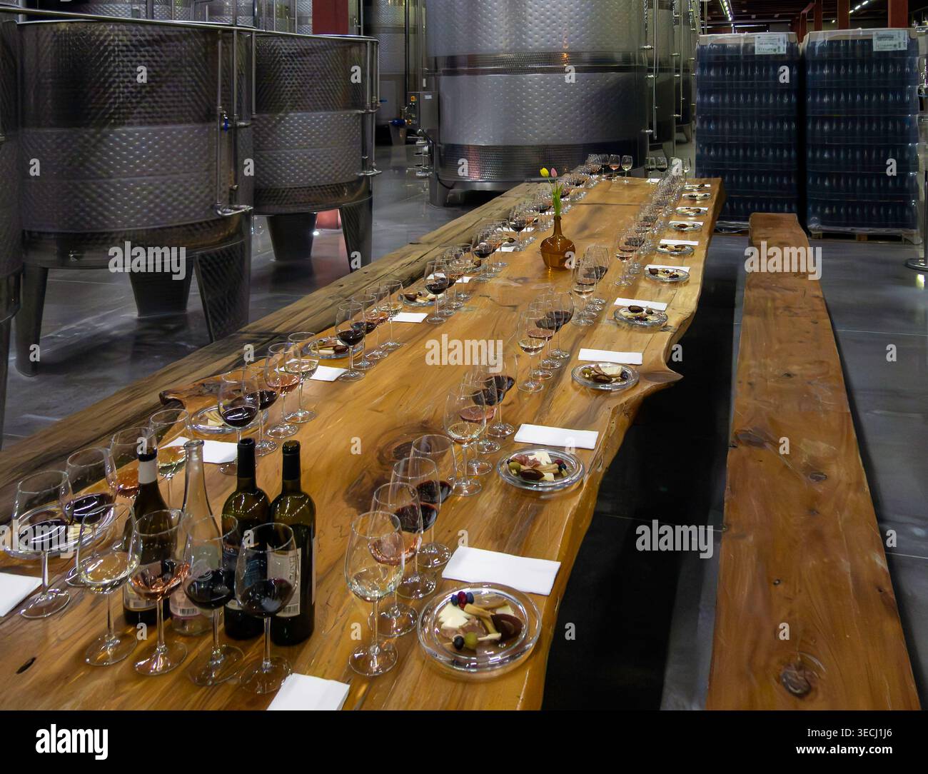 Long wooden table laid out in preparation for a wine tasting event in the cellar of a winery Stock Photo