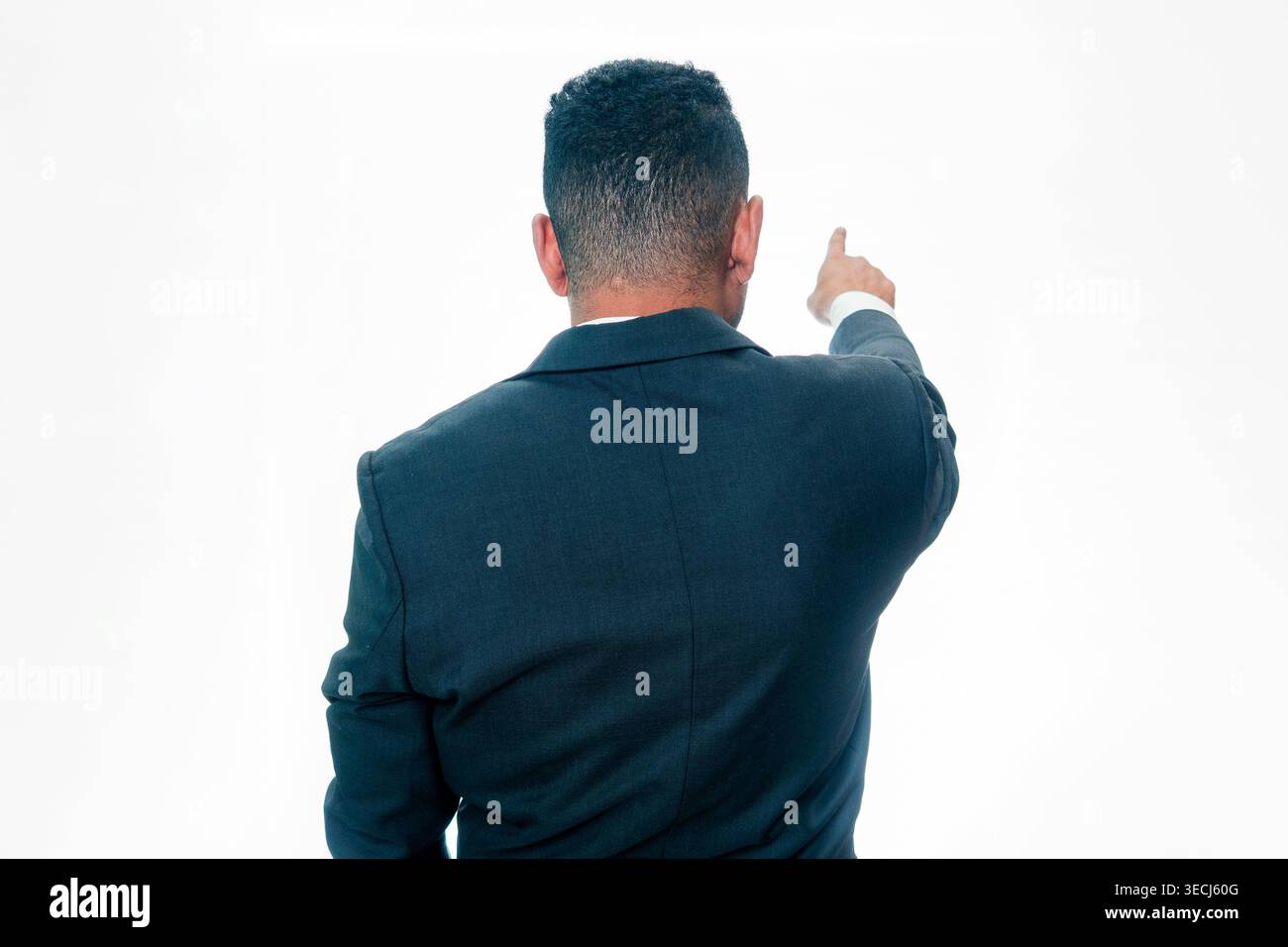Rear view of an Indonesian man in a black suit pointing his finger forward to show direction or vision, isolated on a white background. Stock Photo