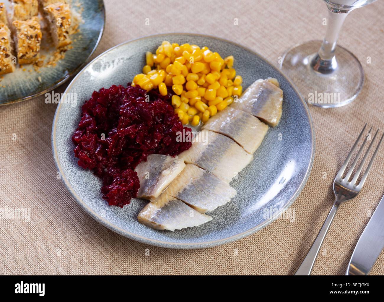 Herring served on plate with grated beetroot and corn Stock Photo