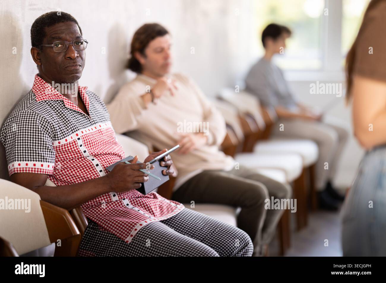 Middle-aged man sitting in a queue at a modern office Stock Photo