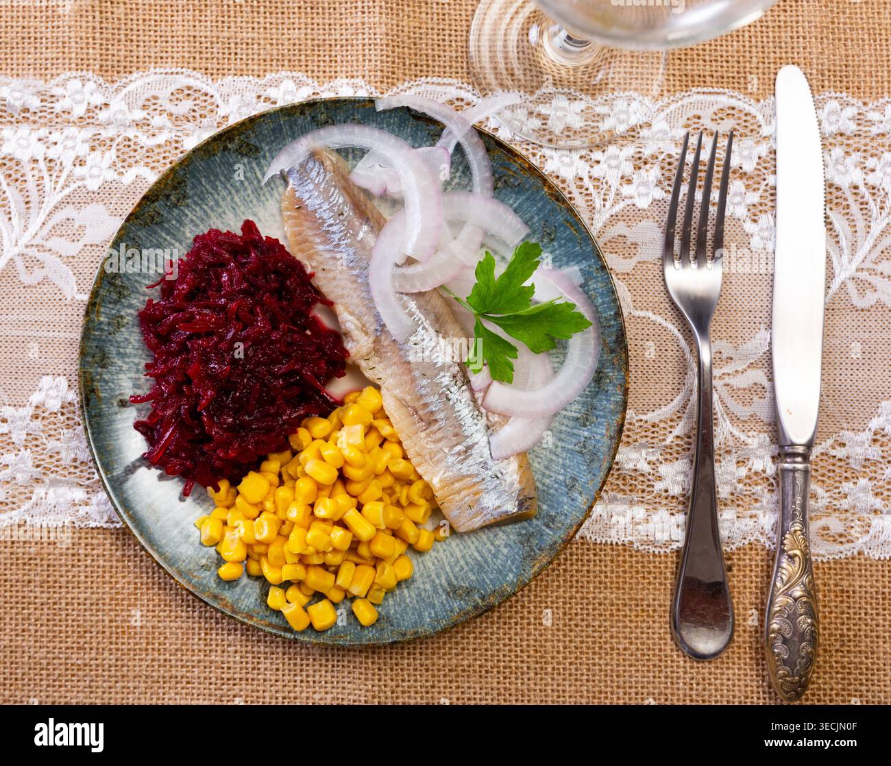 Herring served on plate with grated beetroot and corn Stock Photo