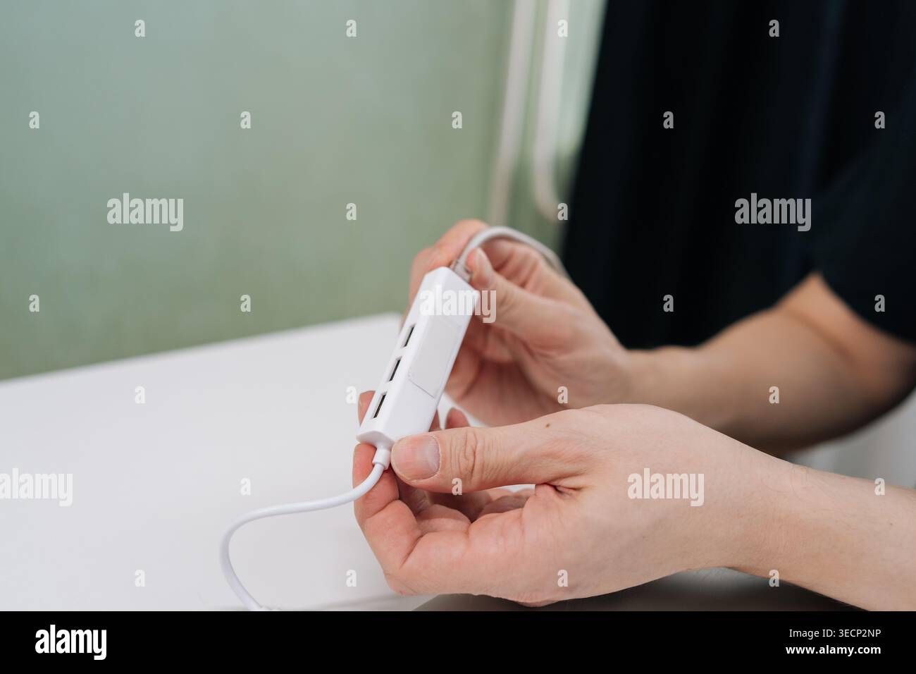 Hands holding white USB hub with multiple ports, poised to connect devices for expanded data transfer, charging and connectivity in clean modern Stock Photo