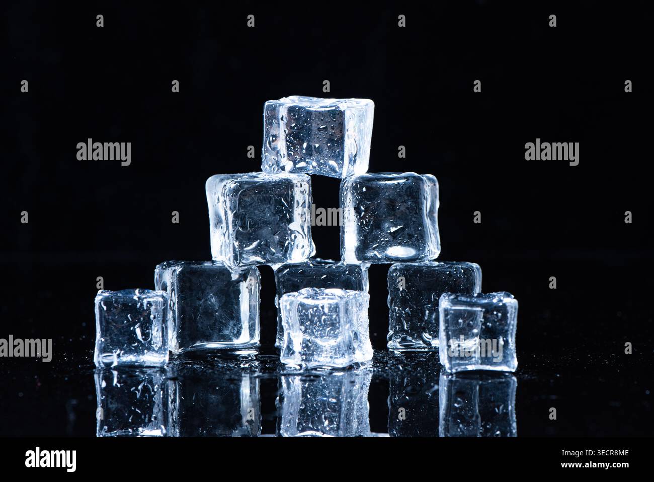 Ice cubes melting on a reflective surface, creating refreshment concept Stock Photo