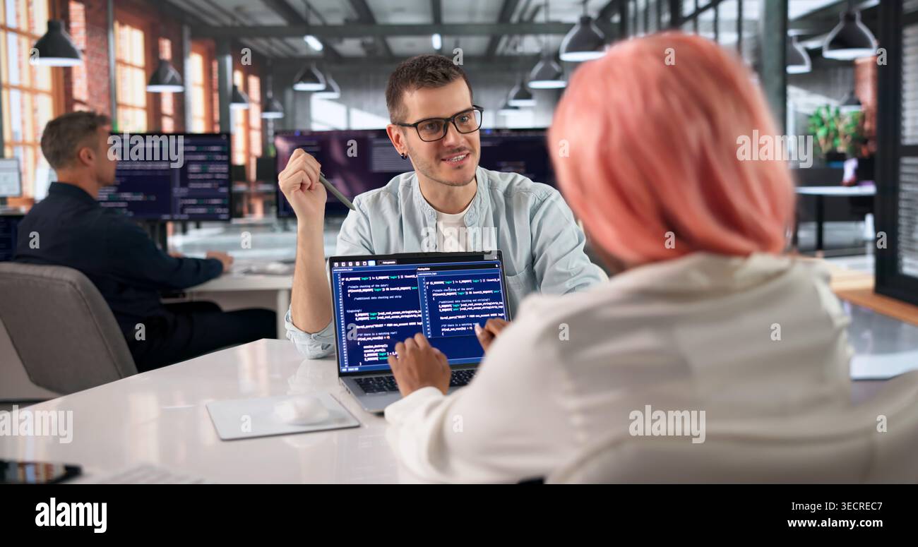 Programmer Collaborates With Diverse Team Coding Software In Modern Office. Stock Photo