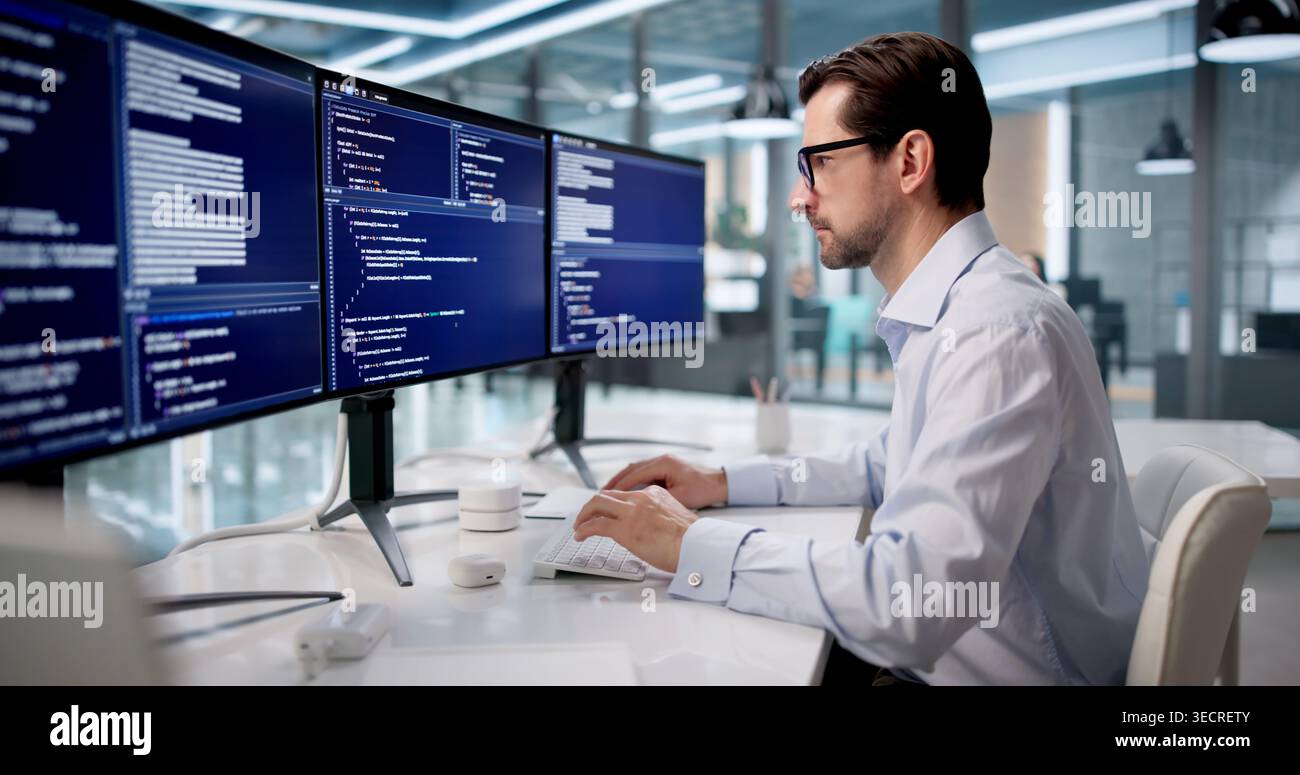 Mature Man Focused On Coding Software At Desk In Modern Office. Stock Photo