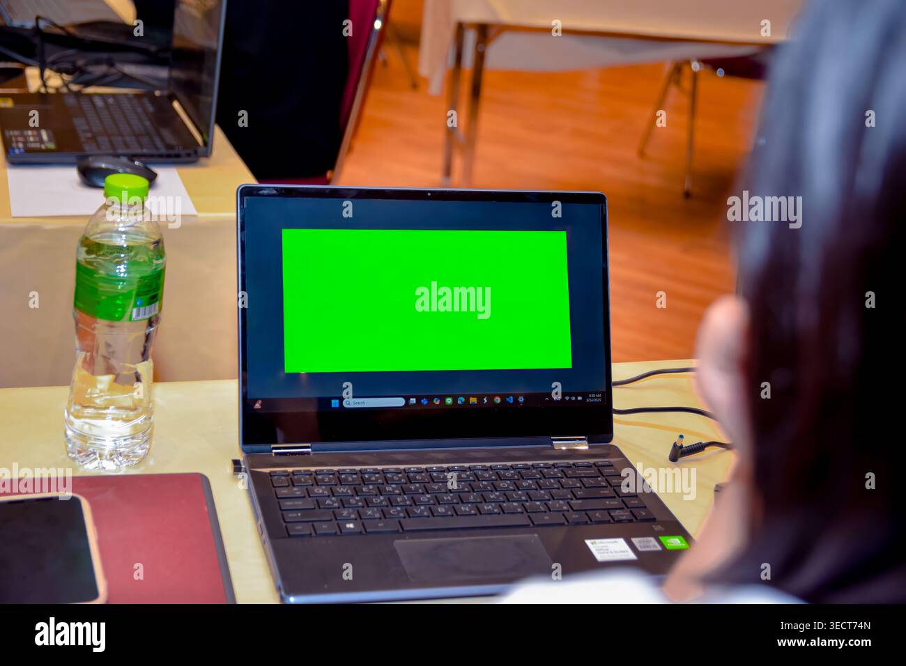An engineer at a computer workstation looking at a green chroma key mockup screen window on a laptop during an engineering software class in Bangkok. Stock Photo