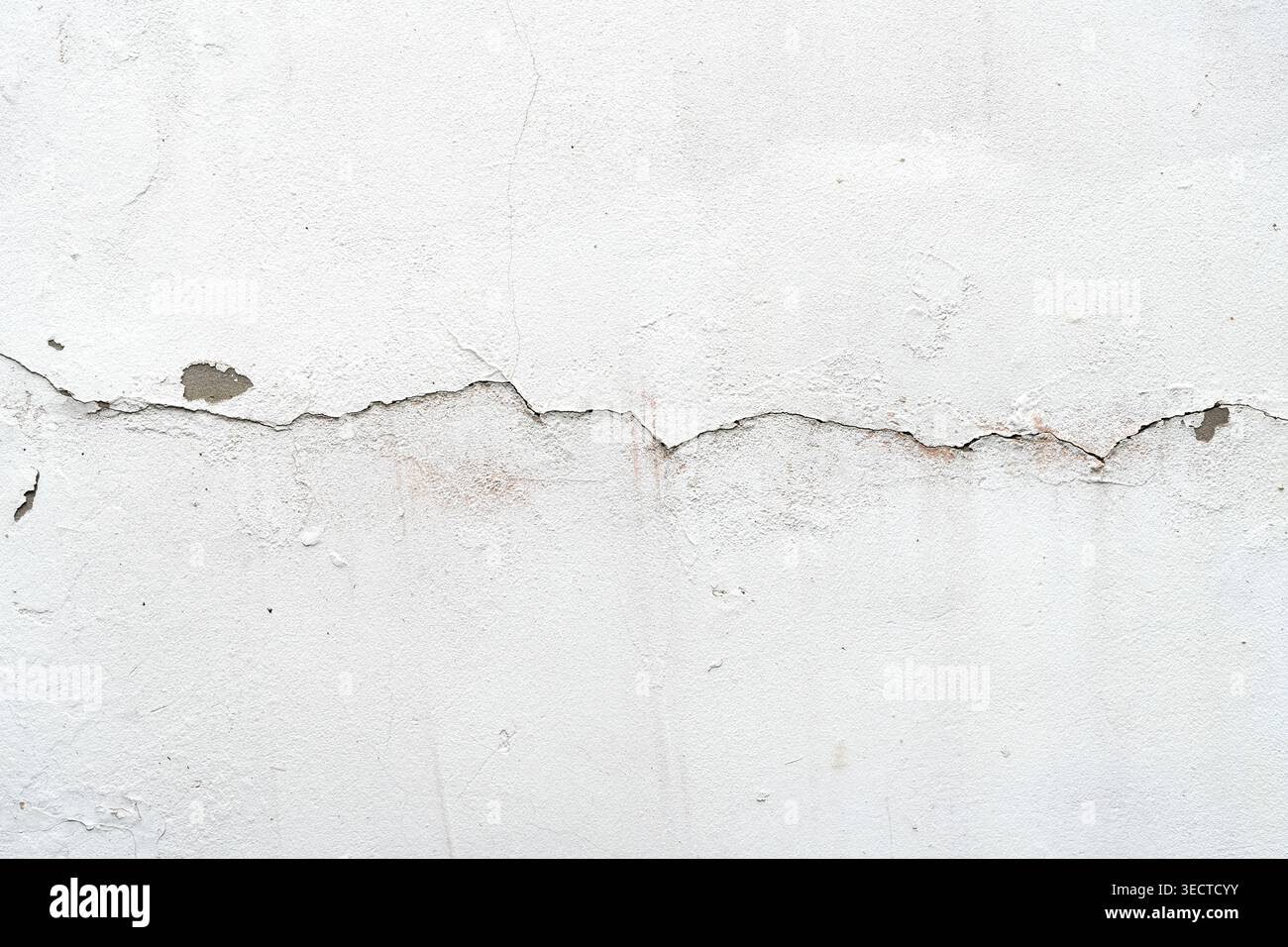 Close up of old white plaster wall with large crack and peeling texture Stock Photo