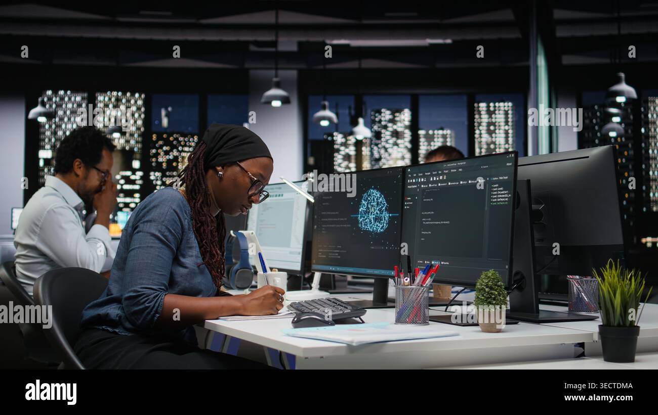 Programmer taking notes at desk in Silicon Valley company office, developing apps. IT expert using machine learning to do coding, writing on notepad, debugging applications to resolve issues Stock Photo