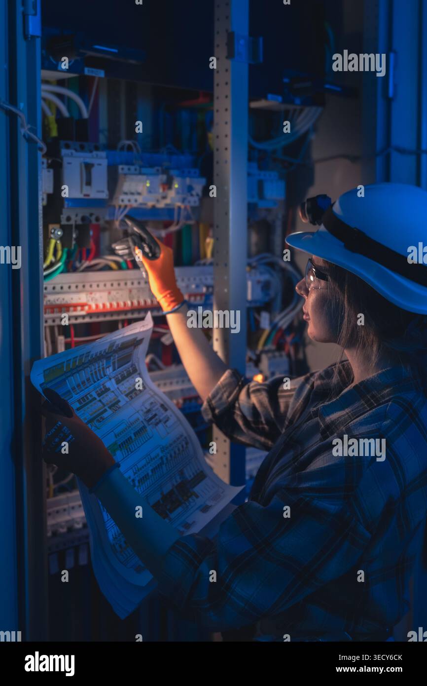 Electrical engineer inspecting power system blueprint near switchboard. Professional inspection. Stock Photo