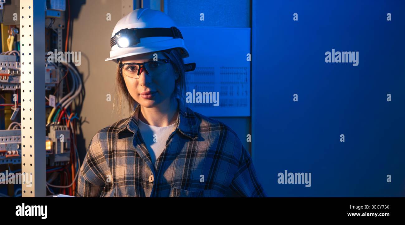 Electrical engineer standing near switchboard holding system blueprint. Professional portrait. Stock Photo