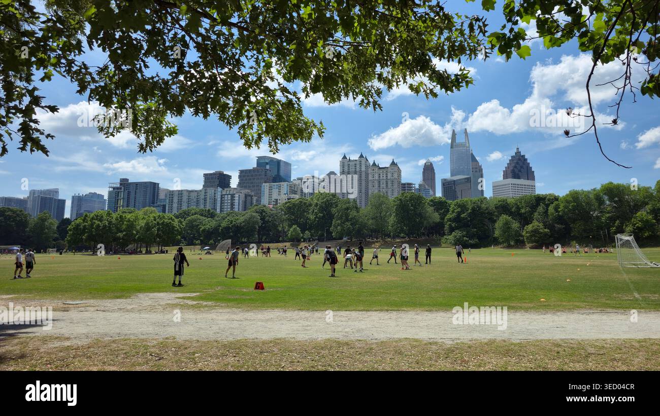 People playing recreational sports on open fields in Piedmont Park with the Midtown Atlanta skyline in the background on a sunny day, usa - Smartphone Captured Stock Image