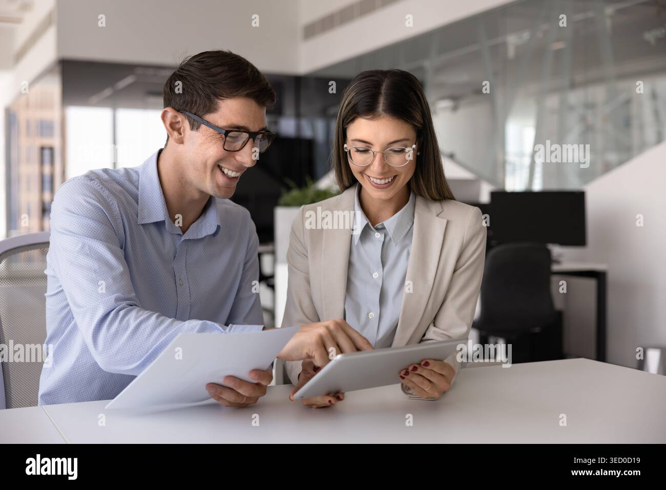 Colleagues using tablet, holding papers, working on joint project Stock Photo