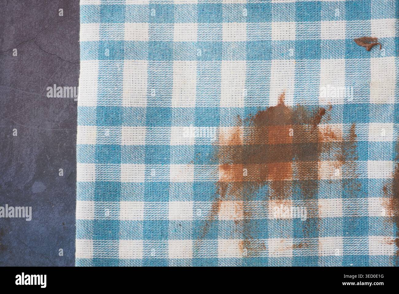Checkered tablecloth with a stain on a dark surface Stock Photo