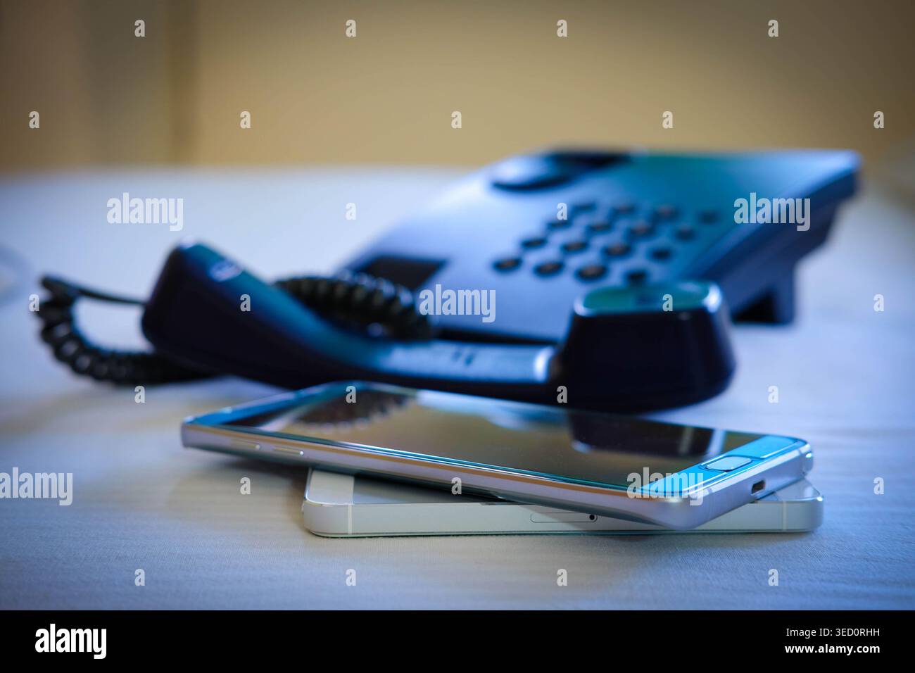 Evolution of communication technology featuring a modern smartphone and an analog office telephone, conceptual comparison of digital and traditional d Stock Photo