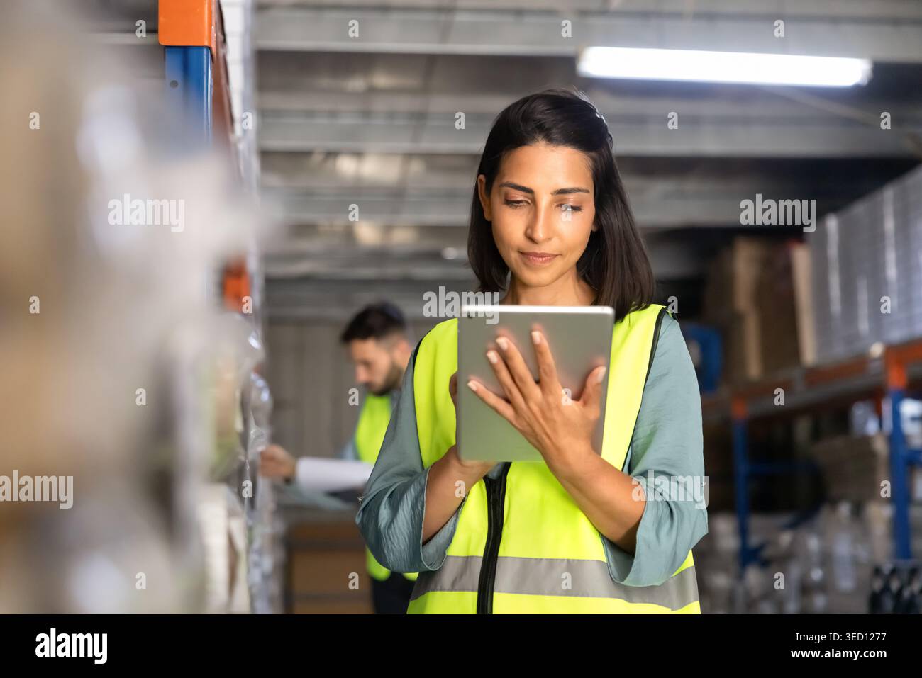 Female worker checking inventory with digital tablet in warehouse Stock Photo