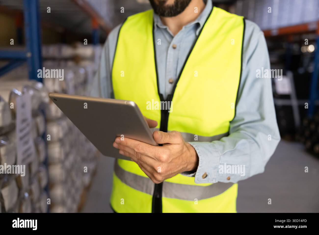 Worker using digital tablet for inventory management in warehouse facility Stock Photo