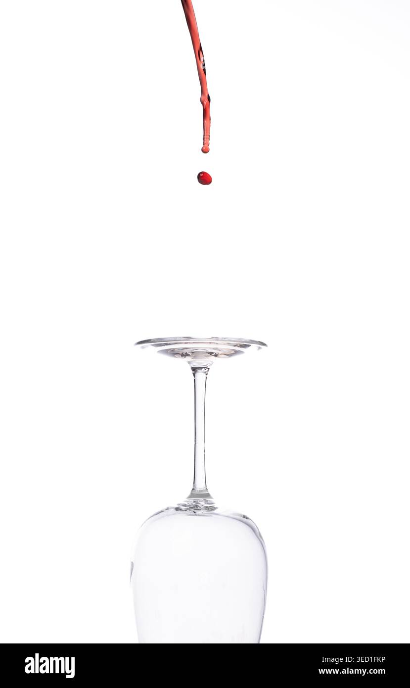 Liquid falls into an empty glass in a studio setting Stock Photo