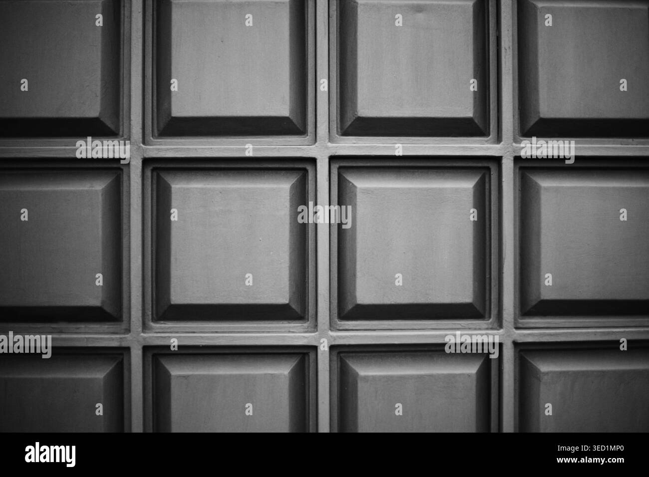 Full frame of a dark gray metal or plastic panel with a repeating square geometric pattern. Stock Photo