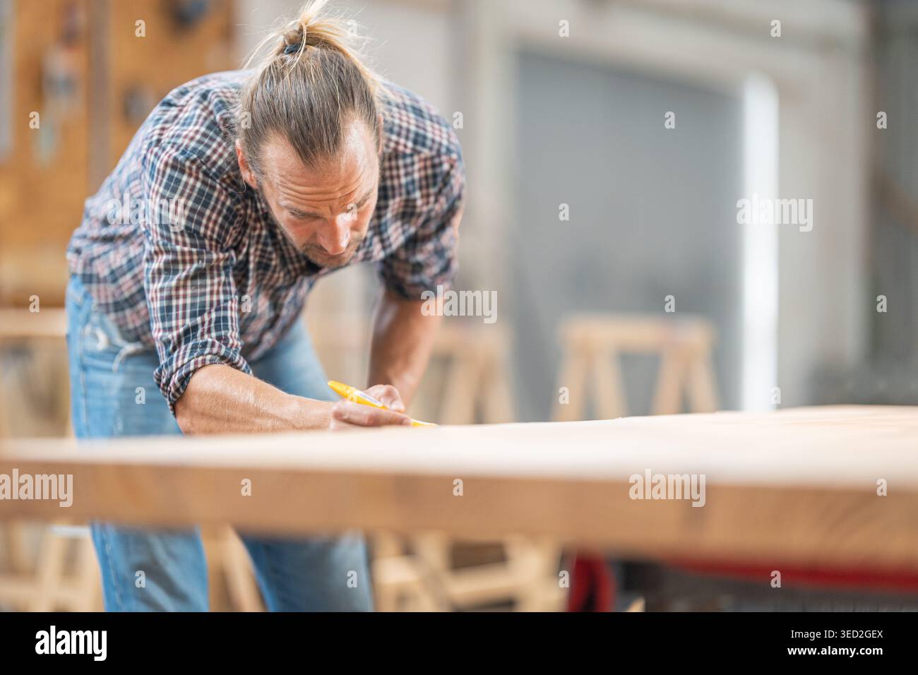 Woodworker precisely marking wooden board in carpentry workshop Stock Photo