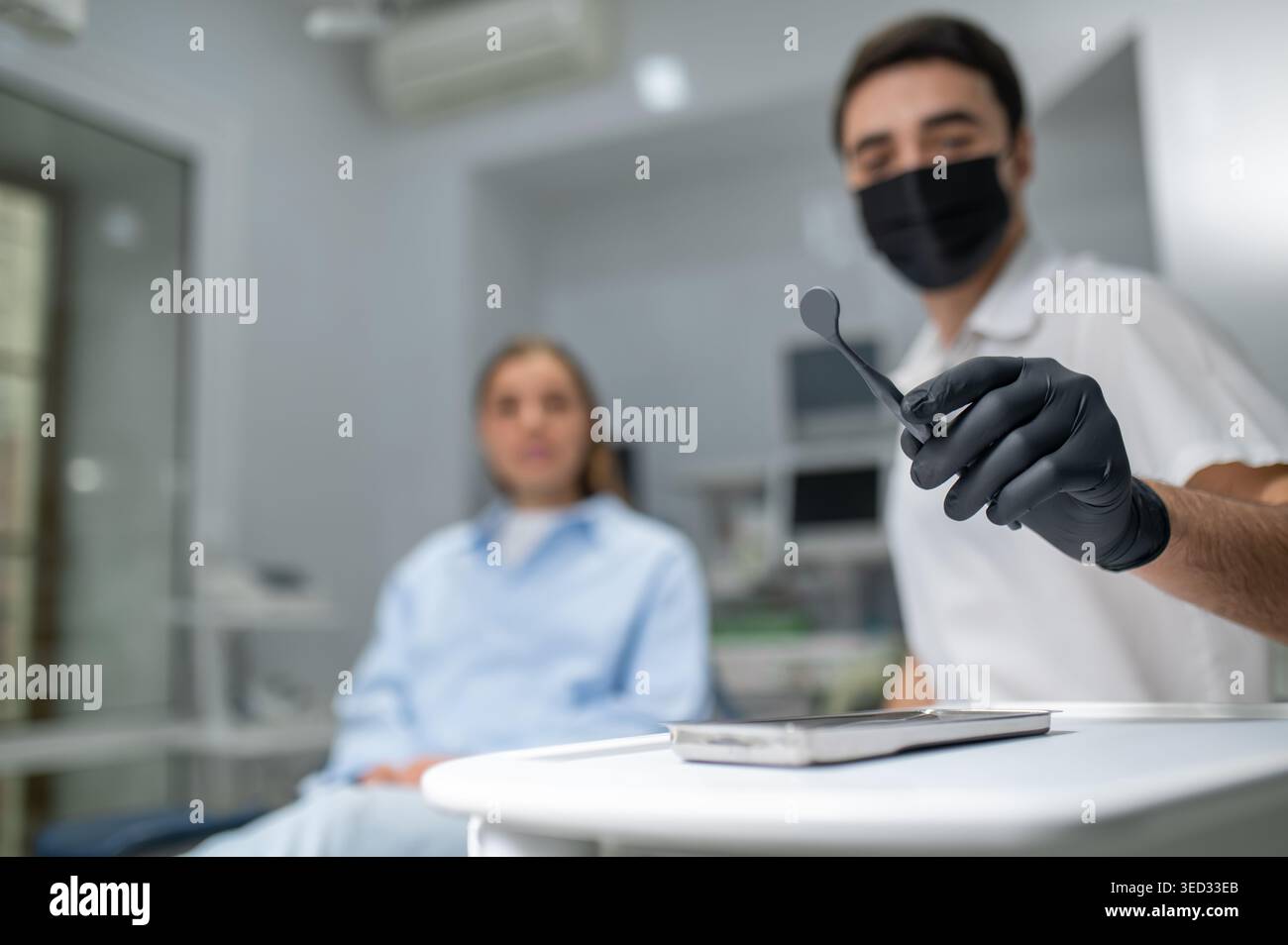 Dentist hands in black gloves holding tools Stock Photo