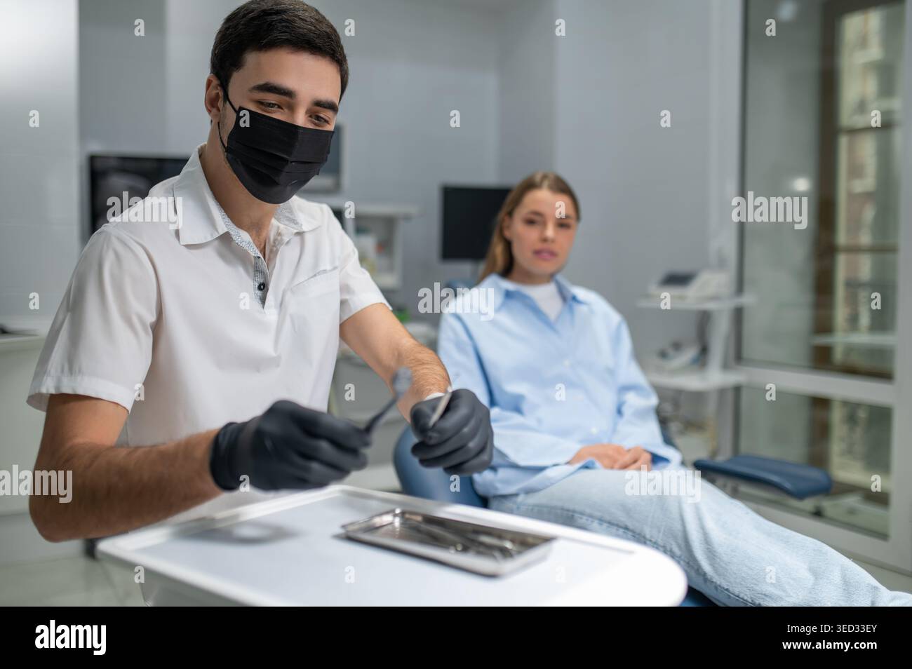 Dentist hands in black gloves with tools Stock Photo