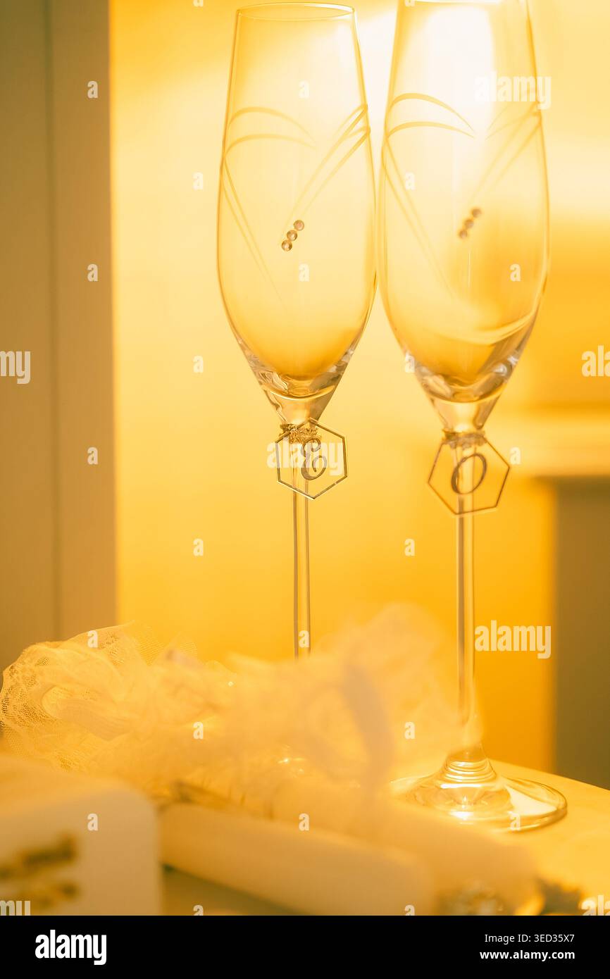 Elegant white heels prepared for wedding celebration. White high heels sit beside two champagne glasses, small gift box, and decorative item. setting Stock Photo
