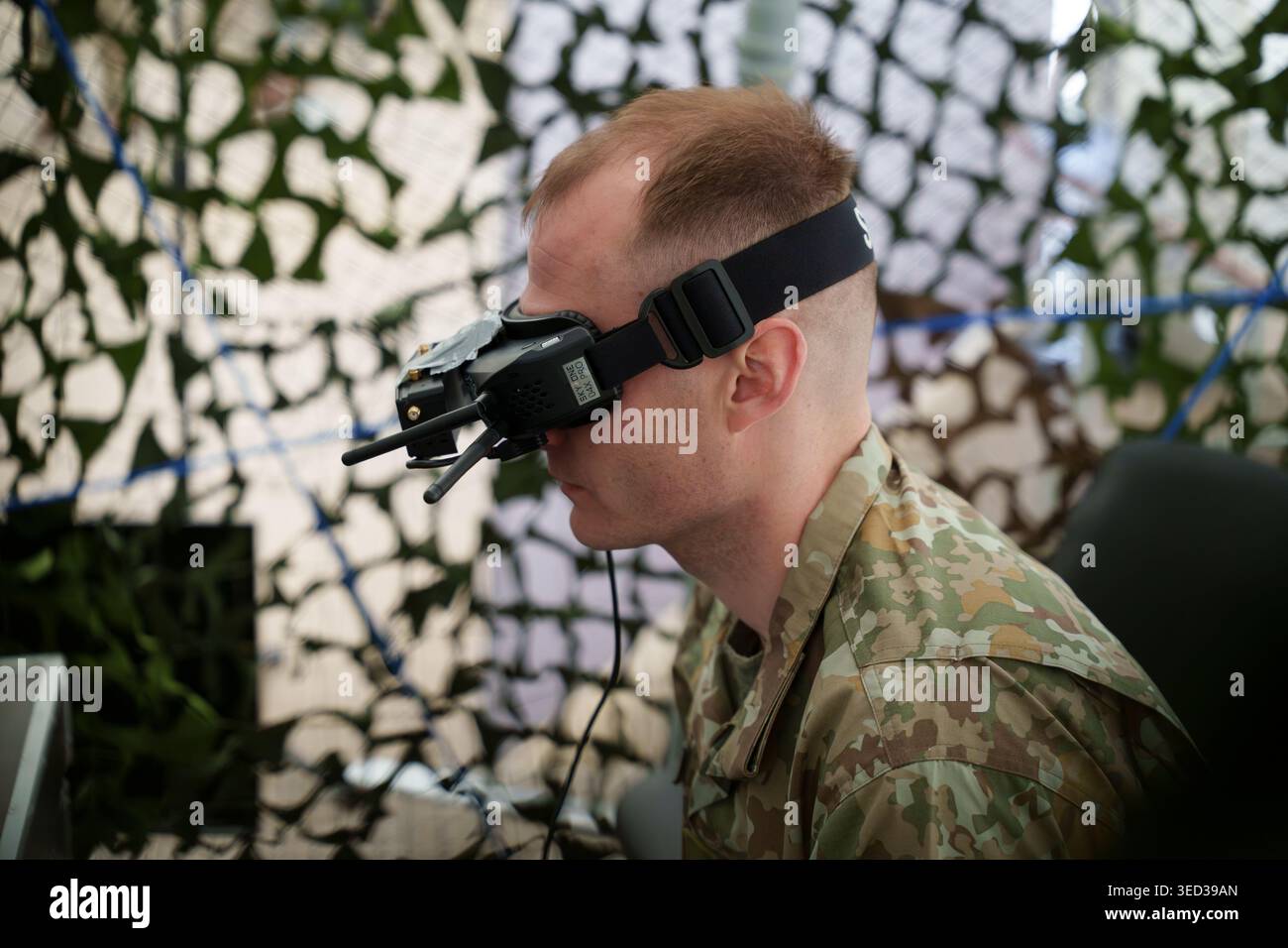 Soldier in camouflage uniform using FPV goggles and remote controller ...