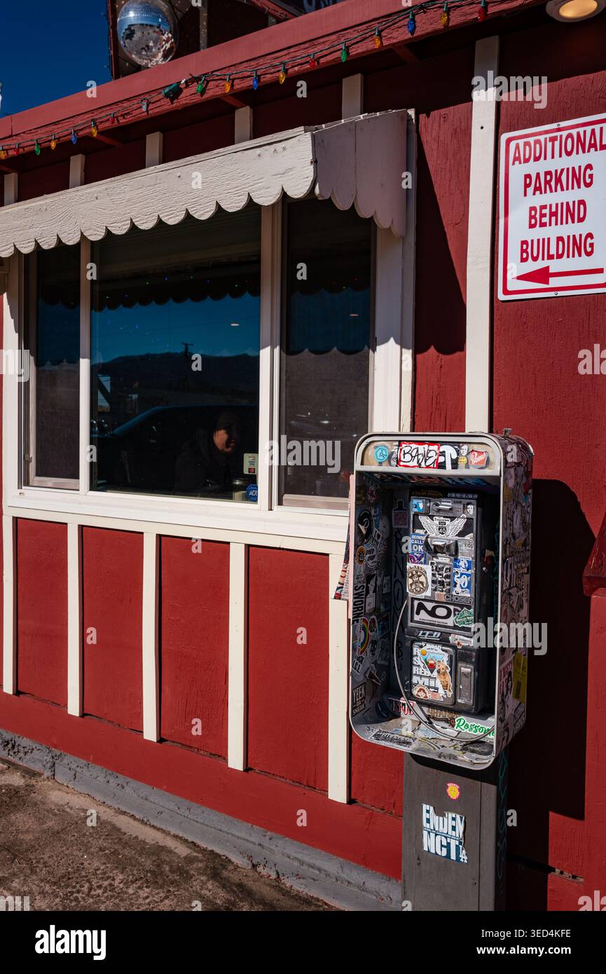 JT Disco Kitchen restaurant storefront in Joshua Tree, California with Sticker-covered public payphone in Joshua Tree, California Stock Photo