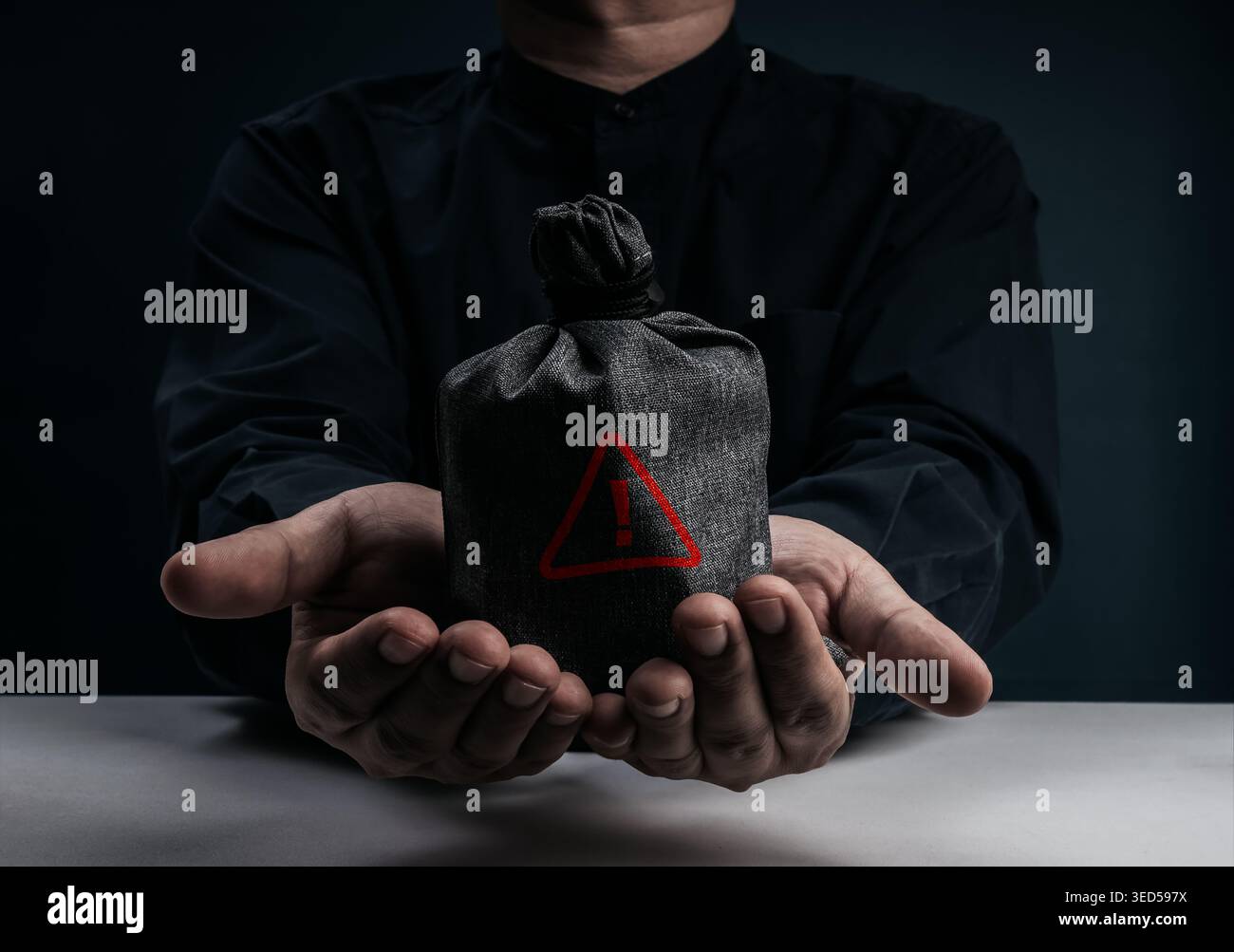 Hands holding dark suspicious money bag with red triangle warning ...