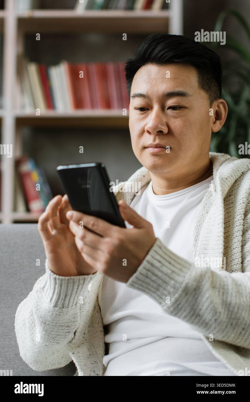 Man Using Smartphone on Couch Stock Photo