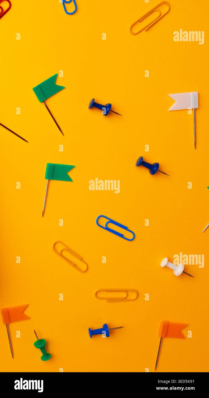 Colorful stationery items scattered on a bright yellow surface during daylight hours Stock Photo
