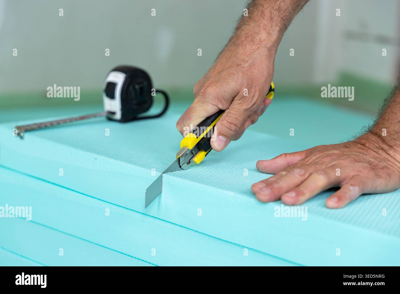 Construction worker cutting insulation boards before laying and fixing on a construction site Stock Photo