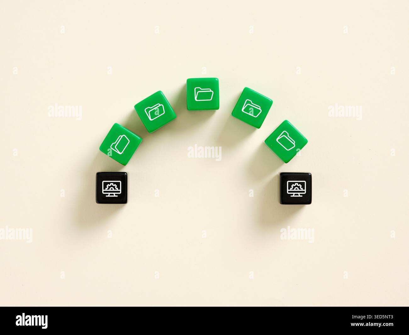 Green dice showing folder icons transferring data to black dice showing computer processing icon representing file sharing and data transfer Stock Photo