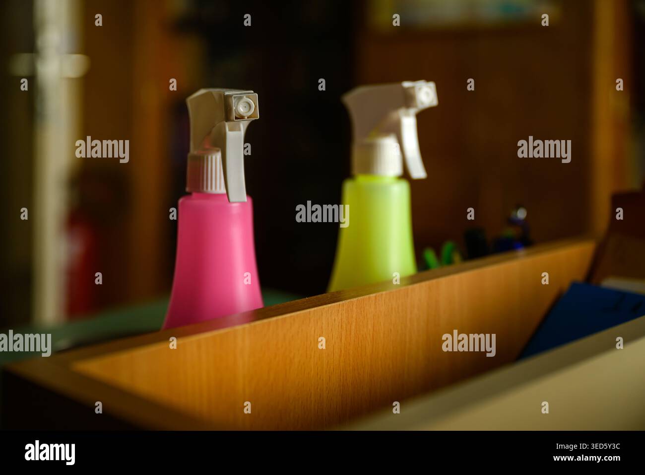 Pink and lime spray bottles in wooden drawer, close-up with selective focus Stock Photo