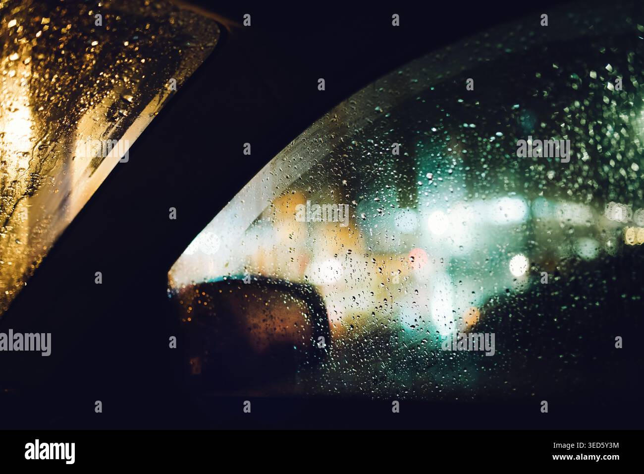 Rainy night car window with city bokeh lights through wet glass, selective focus Stock Photo
