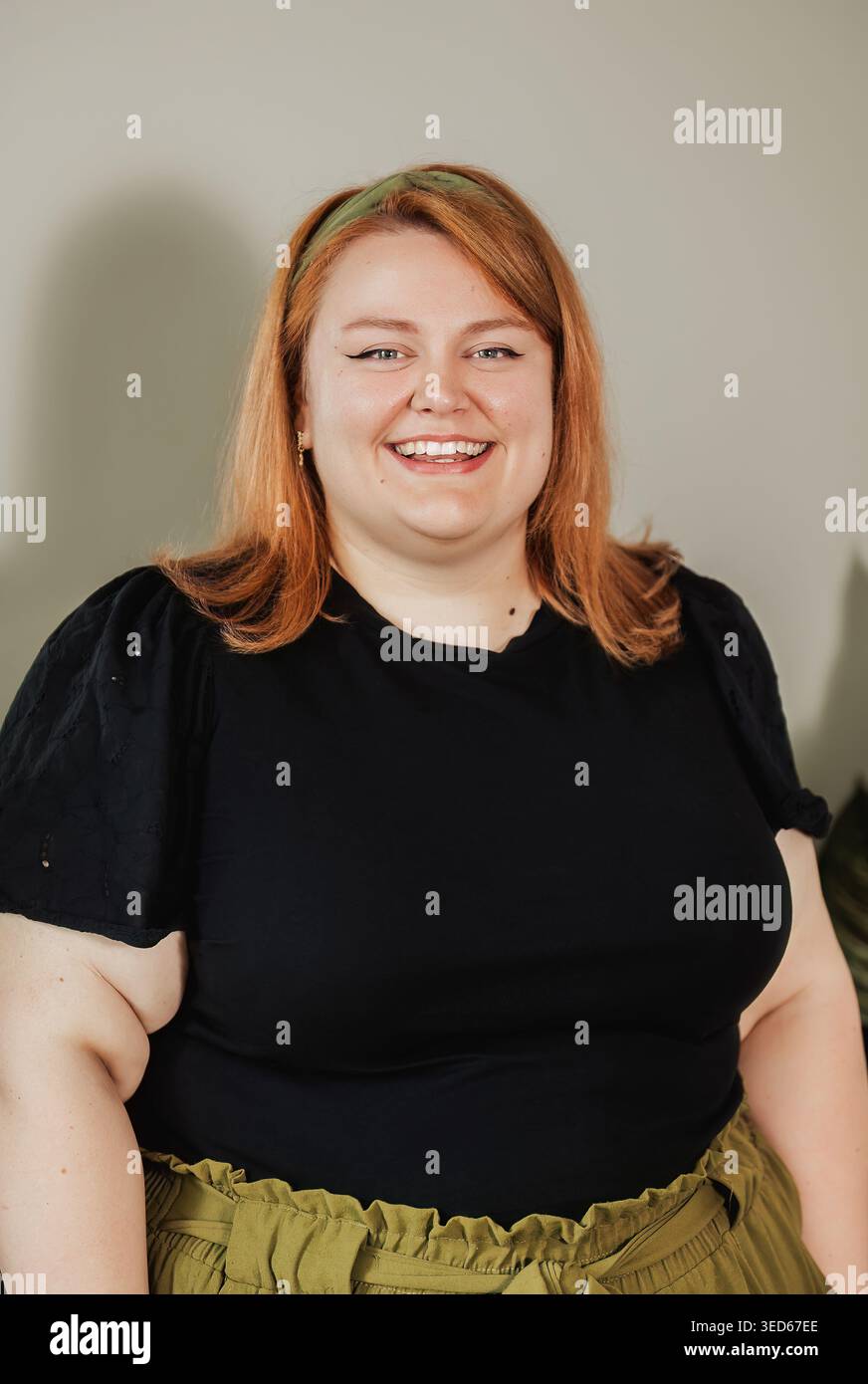 Woman with bright smile, black eyelet top, neutral background Stock Photo