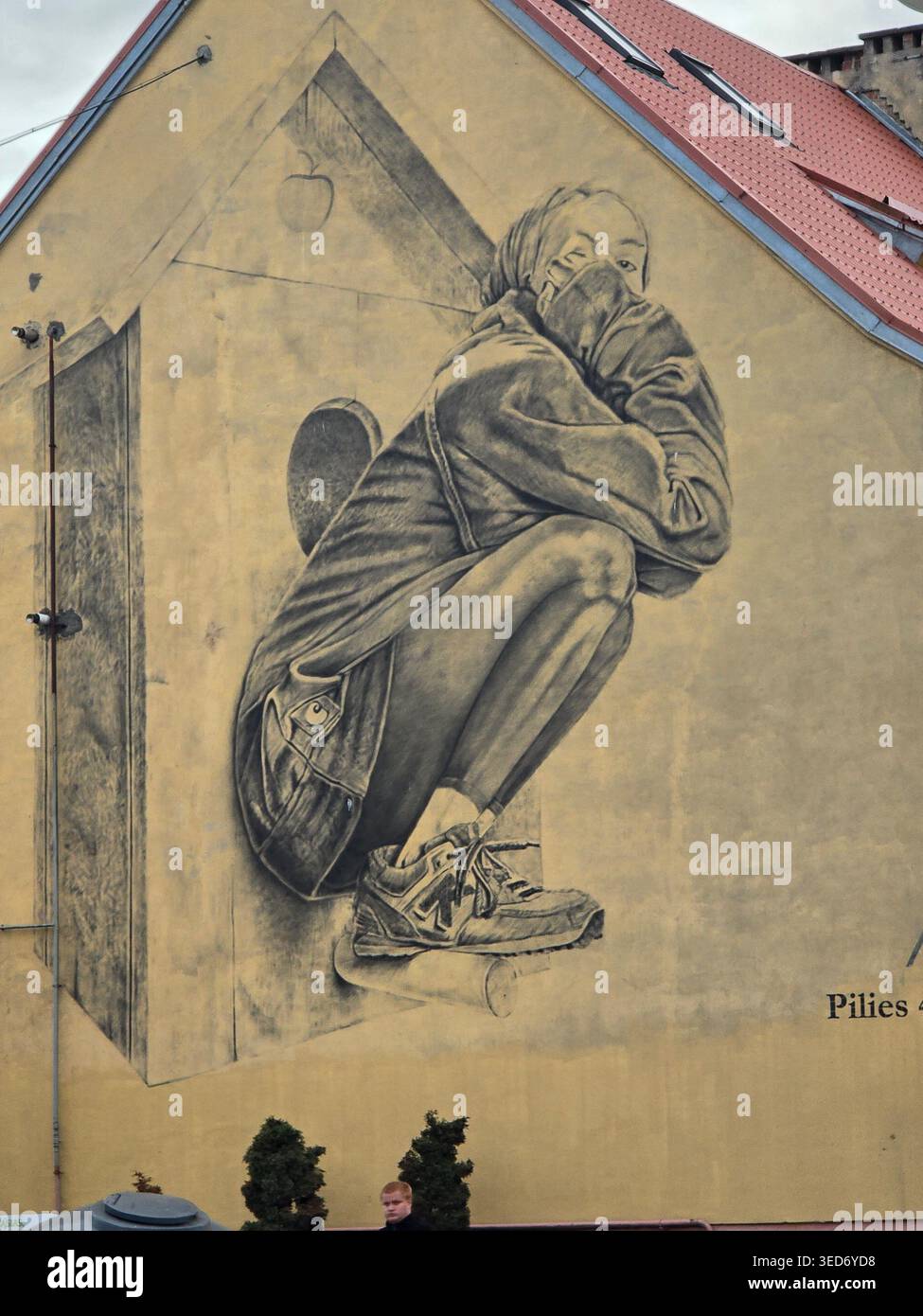 Large-scale monochrome street art mural of a huddled figure on a building facade on Pilies street in Kaunas, Lithuania - Smartphone Captured Stock Image
