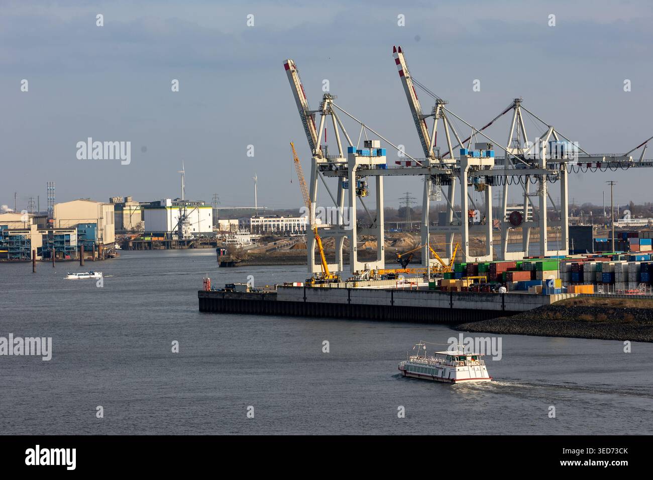 Hamburg port channel with gantry cranes lifting shipping containers ...