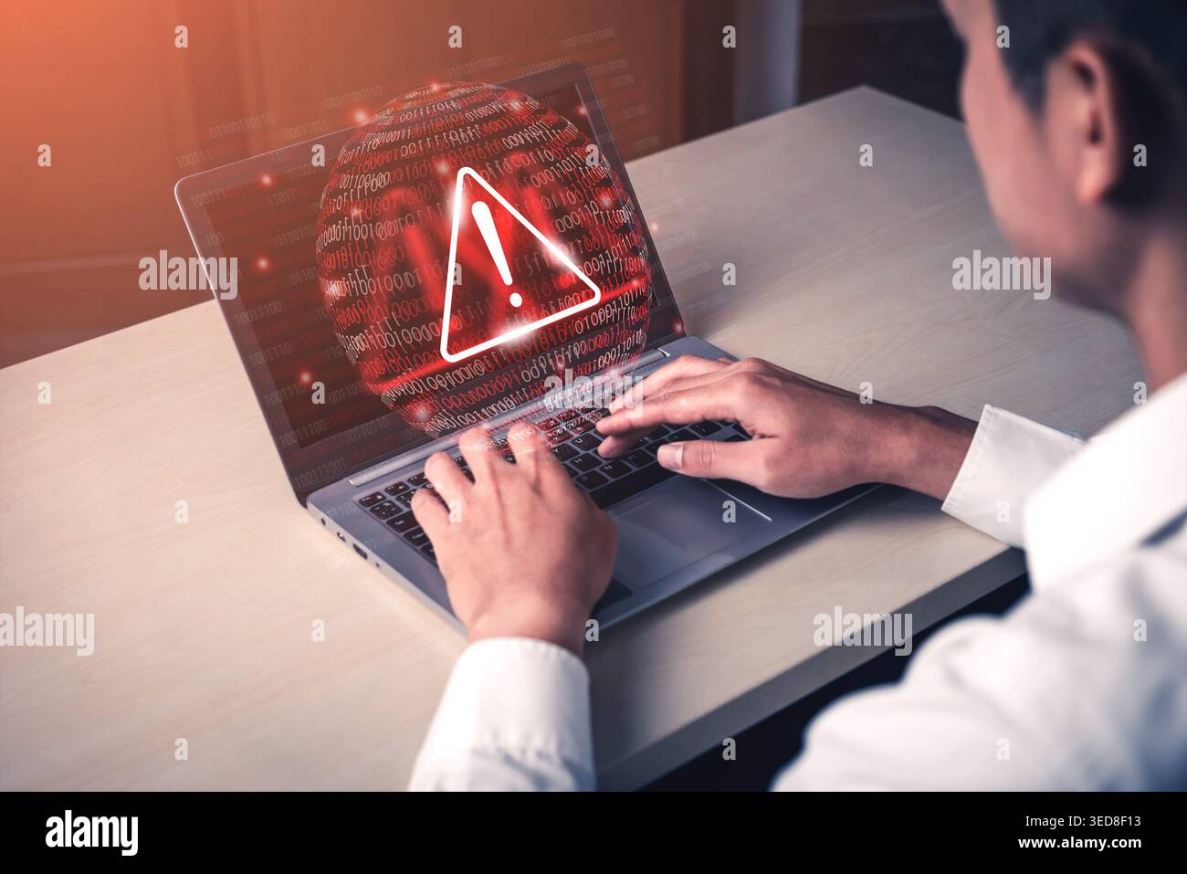 A focused individual interacts with a laptop, highlighting a warning sign on the screen, symbolizing urgent cybersecurity issues and the need for Stock Photo
