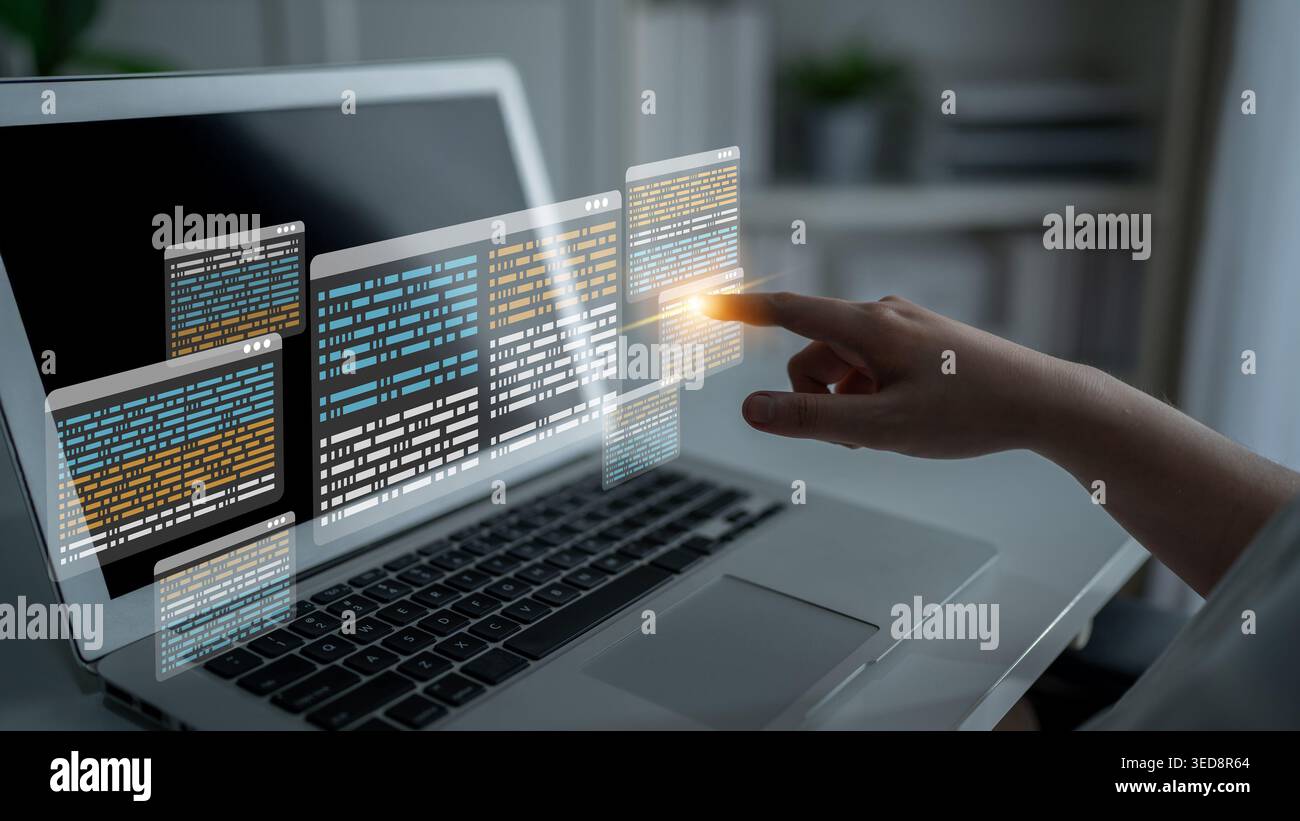A hand interacting with floating digital data displays above a laptop, symbolizing modern technology and innovative programming in a sleek workspace Stock Photo