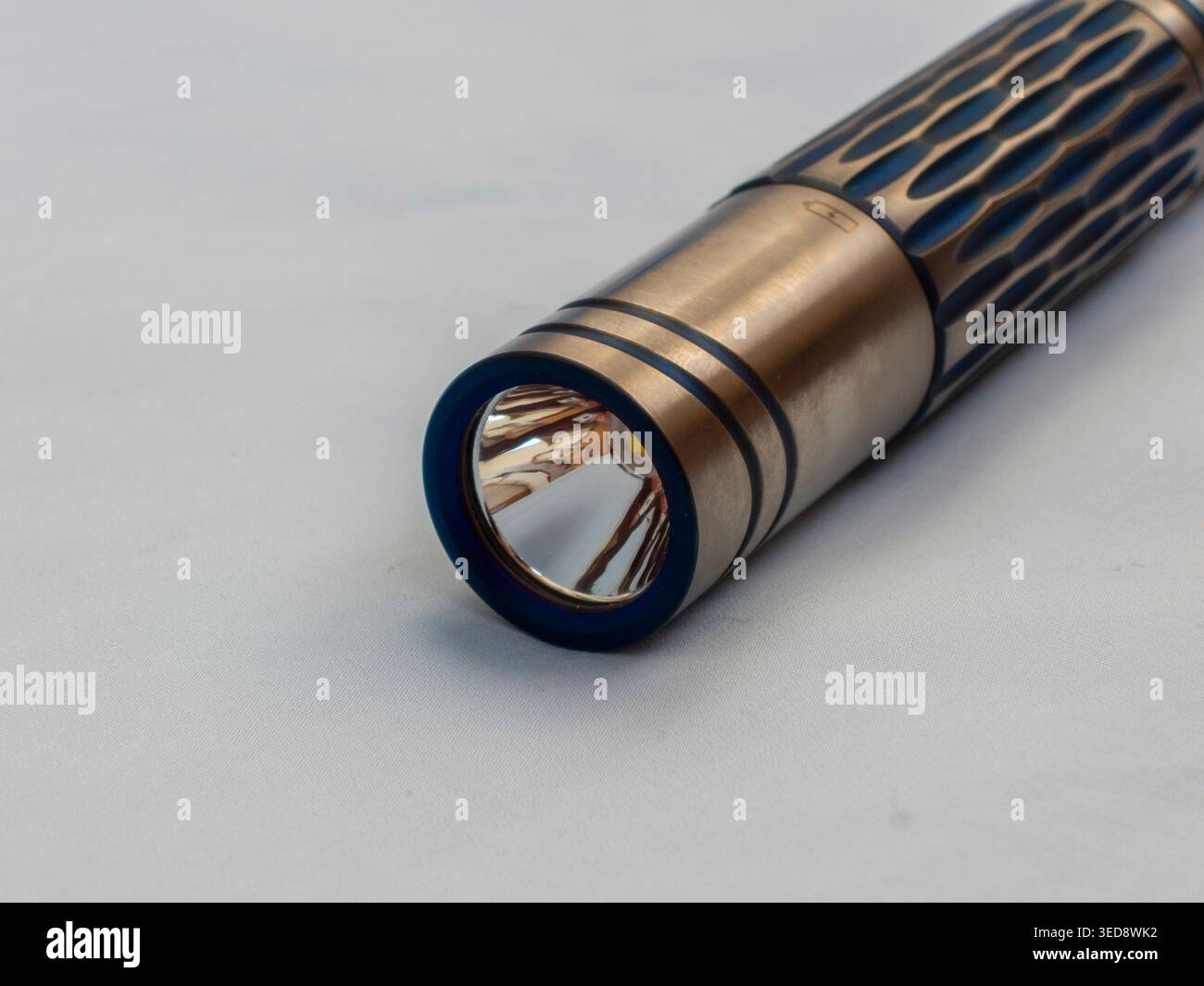 Custom titanium flashlight on sky blue background Stock Photo