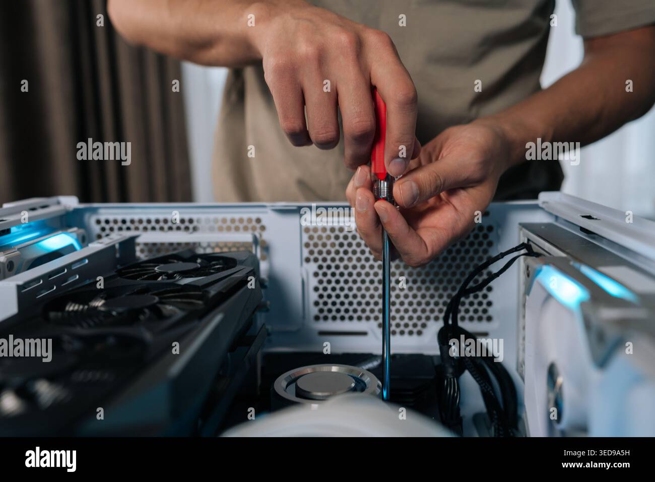 Close-up of technician hands maintaining and upgrading a personal computer, assembling internal hardware components with screwdriver, performing Stock Photo